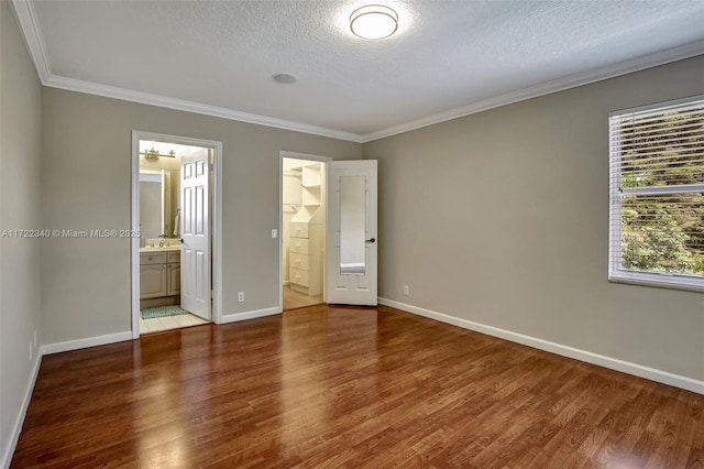 unfurnished bedroom featuring connected bathroom, hardwood / wood-style floors, ornamental molding, and a textured ceiling