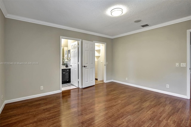 unfurnished bedroom featuring ornamental molding, dark hardwood / wood-style floors, connected bathroom, and a textured ceiling