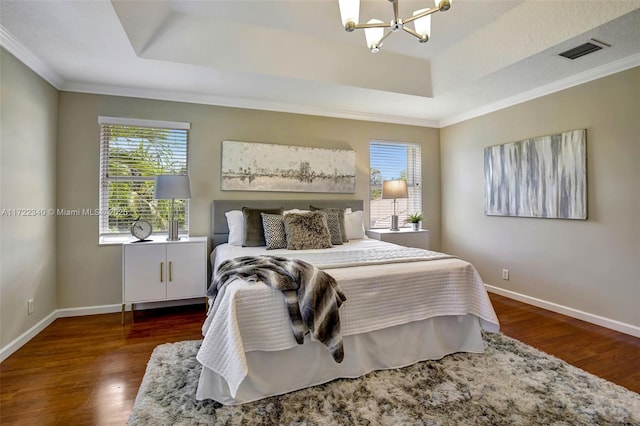 bedroom with a chandelier, dark hardwood / wood-style flooring, a raised ceiling, and crown molding