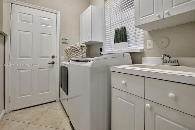 washroom featuring cabinets, sink, washing machine and dryer, and light tile patterned floors