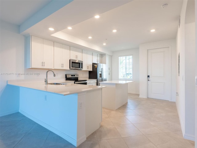 kitchen featuring sink, a kitchen island, kitchen peninsula, white cabinets, and appliances with stainless steel finishes