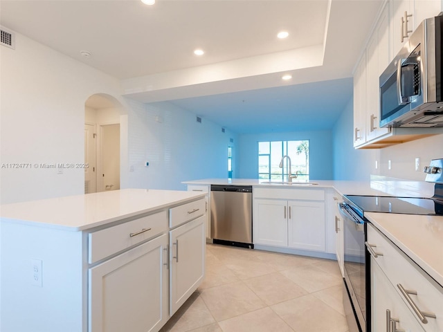 kitchen featuring a center island, sink, light tile patterned floors, white cabinetry, and stainless steel appliances