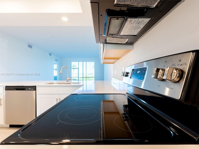 kitchen featuring stainless steel dishwasher, white cabinets, kitchen peninsula, and sink