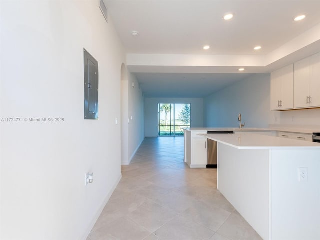 kitchen featuring white cabinetry, a center island, sink, kitchen peninsula, and electric panel