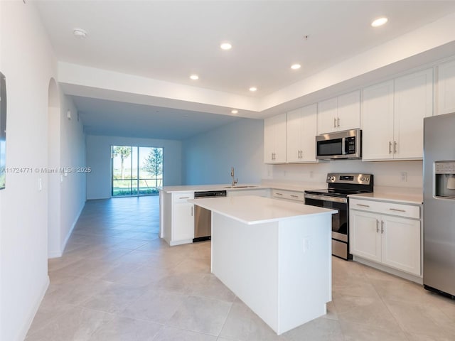 kitchen with a kitchen island, kitchen peninsula, white cabinetry, and appliances with stainless steel finishes