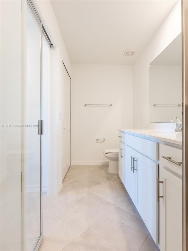 bathroom featuring tile patterned floors, vanity, toilet, and walk in shower