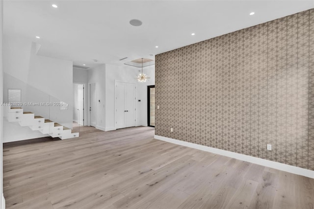 empty room with light hardwood / wood-style flooring and a chandelier