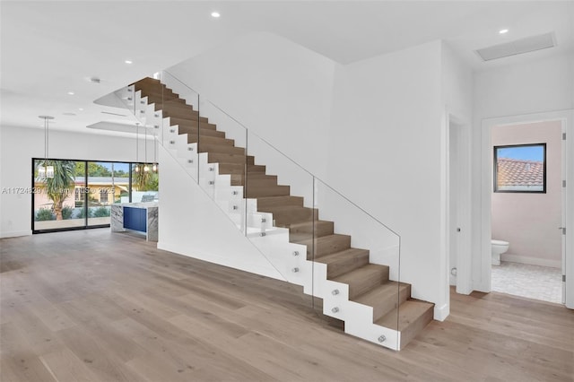 stairway featuring wood-type flooring and an inviting chandelier