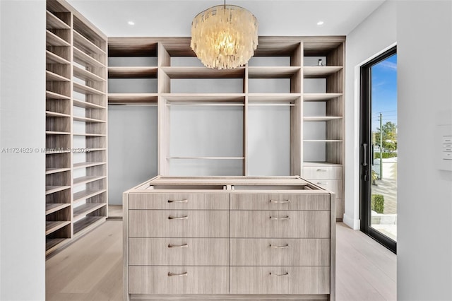 spacious closet featuring a chandelier and light wood-type flooring