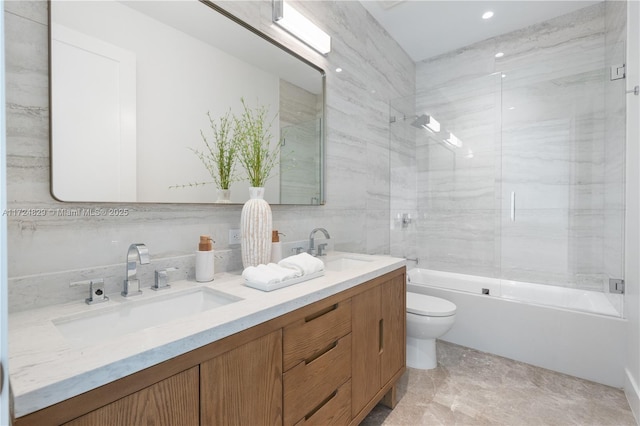 full bathroom with vanity, tile walls, toilet, and tiled shower / bath