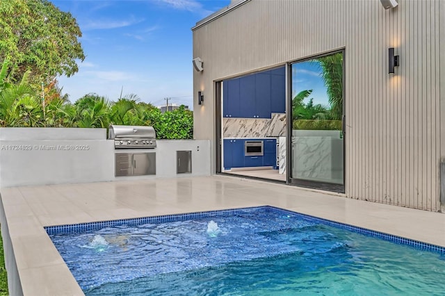 view of swimming pool featuring exterior kitchen, a patio, and a grill