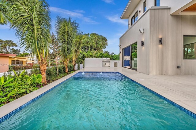 view of pool featuring a patio, an outdoor kitchen, a grill, and pool water feature