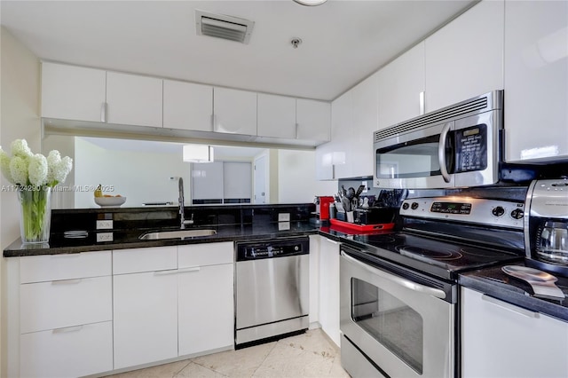 kitchen featuring dark stone countertops, white cabinetry, sink, and stainless steel appliances