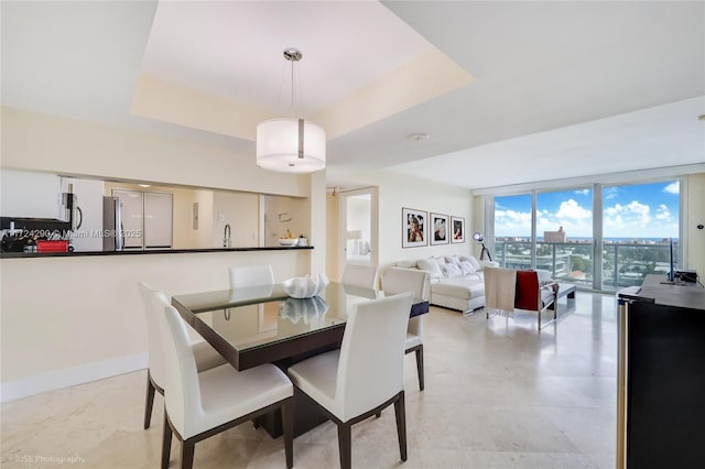 dining room featuring a raised ceiling and a wall of windows