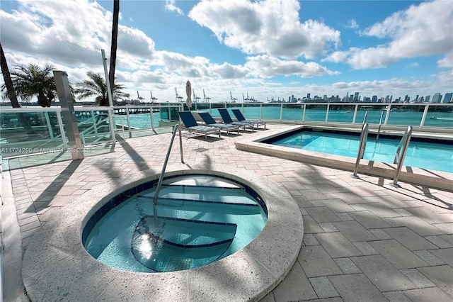 view of swimming pool featuring a water view and a hot tub