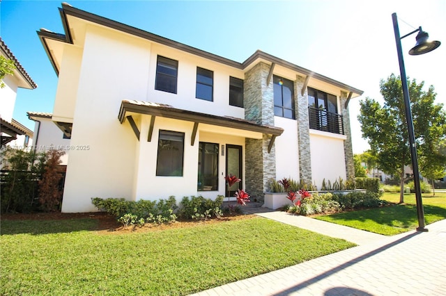 view of front of property with stucco siding, a front yard, and stone siding