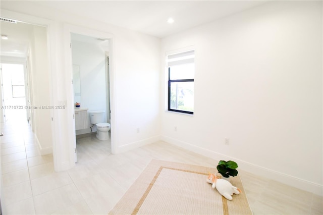 unfurnished bedroom featuring light tile patterned flooring and ensuite bath