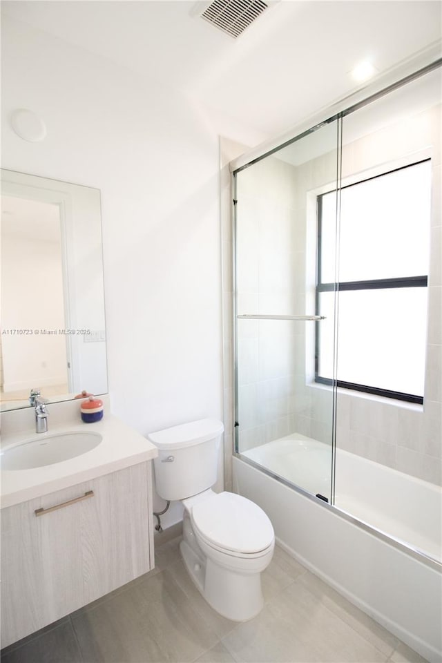 full bathroom with enclosed tub / shower combo, vanity, tile patterned floors, and toilet