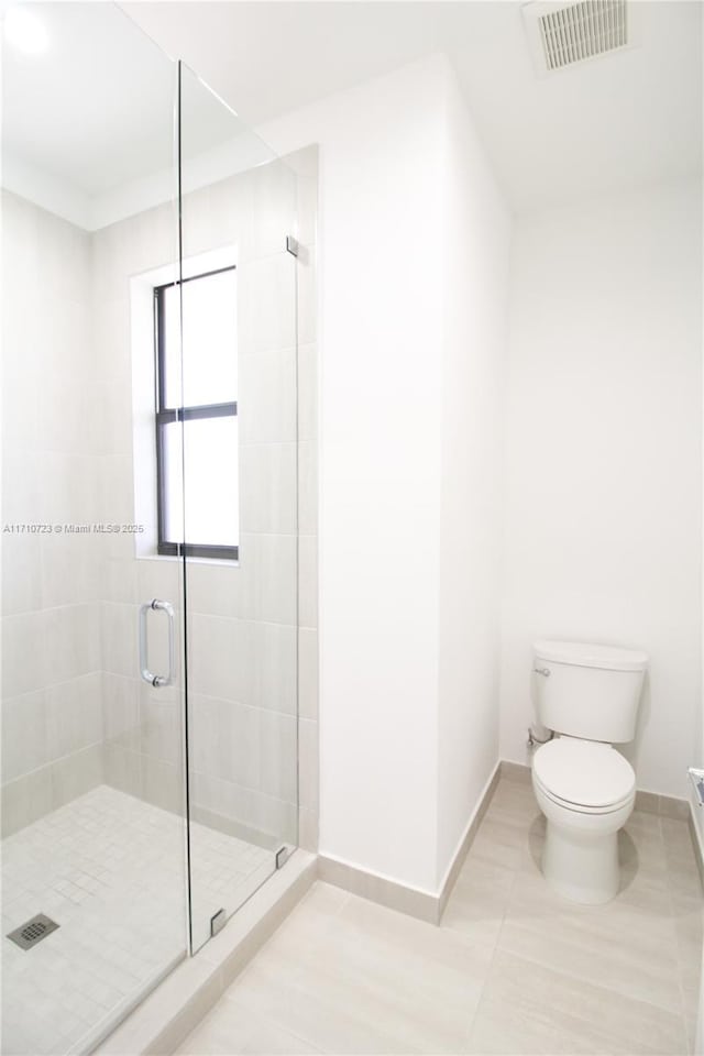 bathroom featuring tile patterned flooring, walk in shower, and toilet