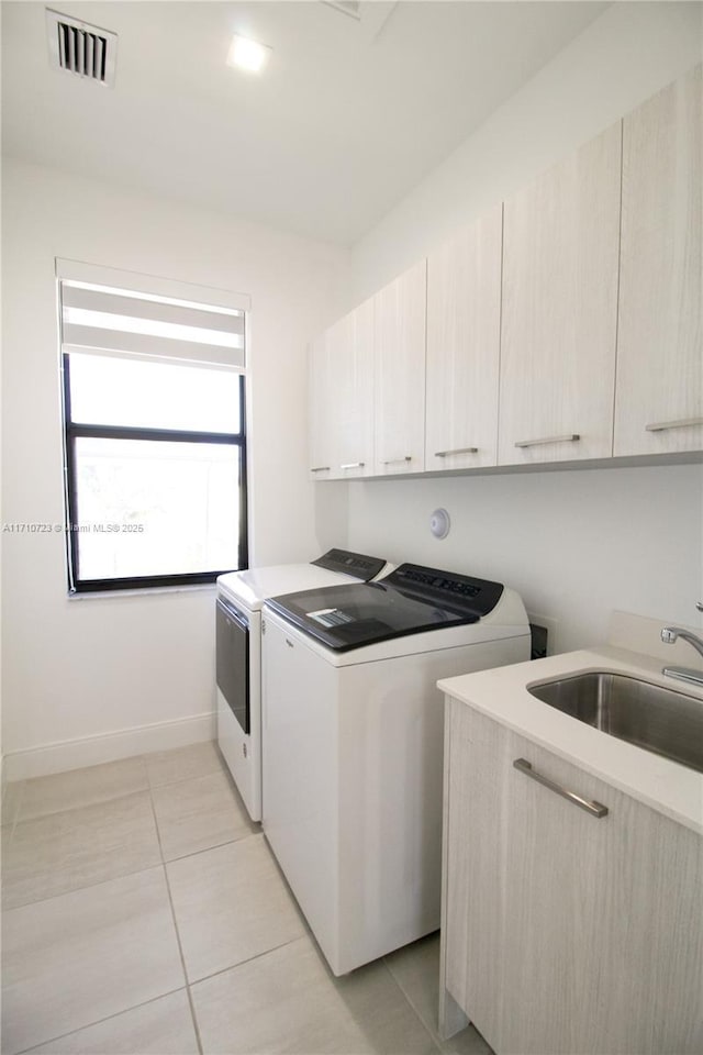 laundry room featuring cabinets, sink, washing machine and dryer, and light tile patterned floors