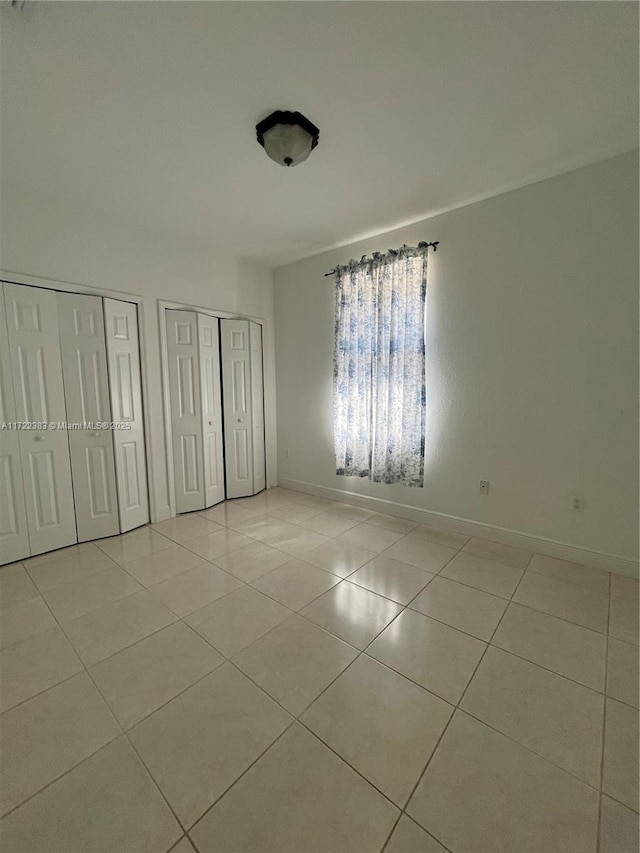 unfurnished bedroom featuring multiple closets and light tile patterned floors