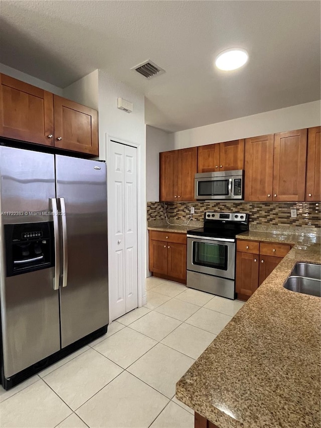 kitchen featuring sink, decorative backsplash, stainless steel appliances, and light tile patterned flooring