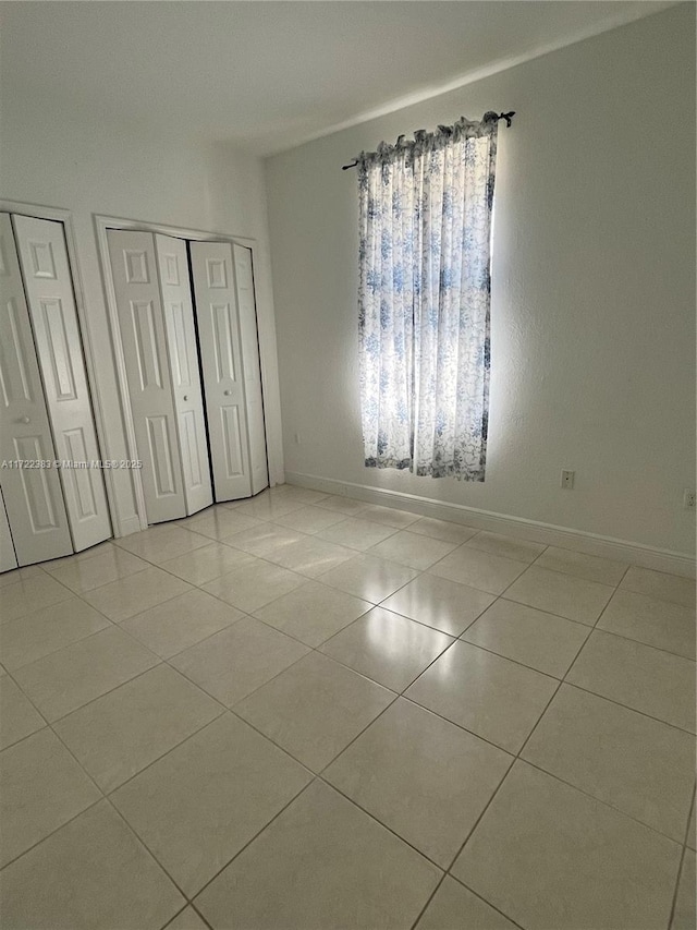 unfurnished bedroom with multiple closets and light tile patterned floors