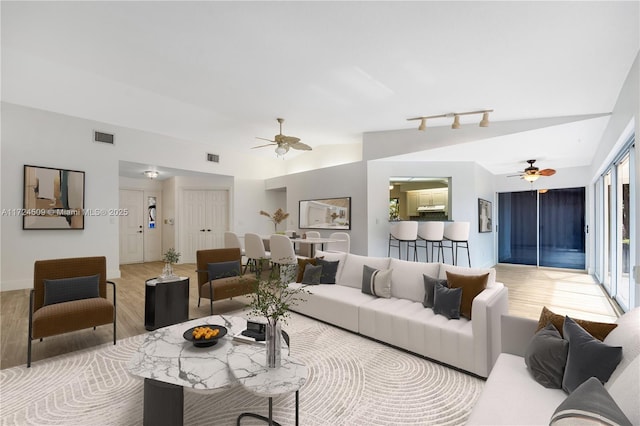 living room with ceiling fan, light hardwood / wood-style flooring, and vaulted ceiling