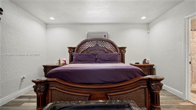 bedroom with ensuite bathroom, a textured ceiling, and hardwood / wood-style flooring