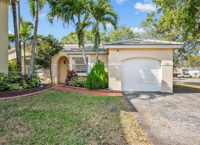 ranch-style house with stucco siding, a front yard, a garage, and driveway