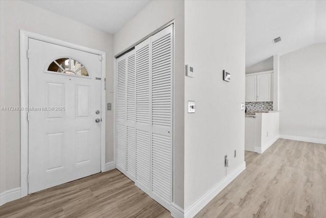 entryway with light hardwood / wood-style floors and vaulted ceiling