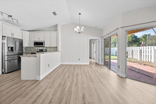 kitchen with lofted ceiling, decorative backsplash, white cabinetry, kitchen peninsula, and stainless steel appliances