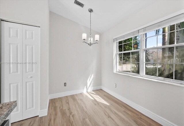 unfurnished dining area with an inviting chandelier and light hardwood / wood-style flooring