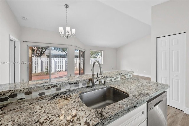 kitchen featuring white cabinets, sink, hanging light fixtures, stainless steel dishwasher, and wood-type flooring