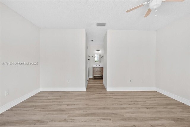 spare room with ceiling fan, light hardwood / wood-style floors, and a textured ceiling