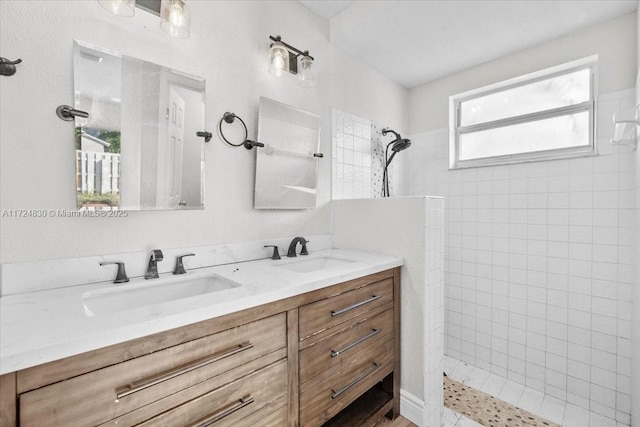 bathroom with tiled shower and vanity