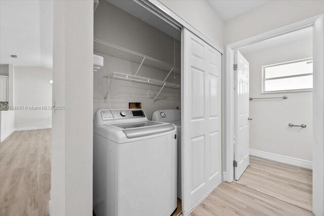 clothes washing area with washer and dryer and light hardwood / wood-style flooring