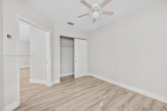 unfurnished bedroom featuring ceiling fan, a closet, a textured ceiling, and light hardwood / wood-style flooring