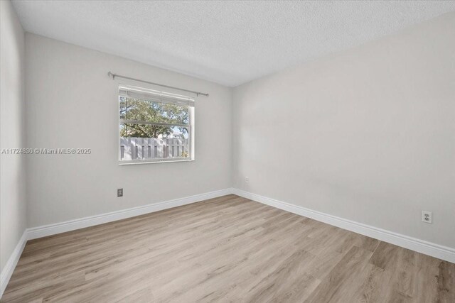 unfurnished room featuring a textured ceiling and light wood-type flooring