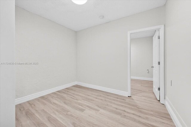 spare room featuring light hardwood / wood-style floors and a textured ceiling