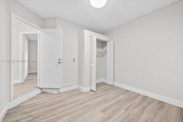 unfurnished bedroom featuring a textured ceiling, light hardwood / wood-style flooring, and a closet