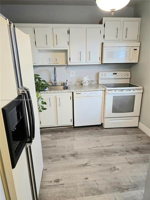 kitchen with white appliances, light hardwood / wood-style floors, white cabinetry, and sink