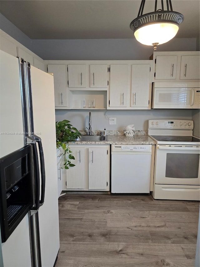 kitchen featuring sink, hanging light fixtures, wood-type flooring, white appliances, and white cabinets