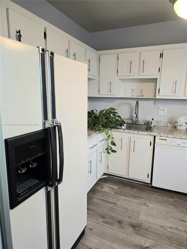 kitchen with sink, white appliances, and hardwood / wood-style flooring