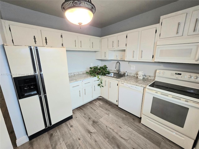 kitchen with white appliances, light hardwood / wood-style floors, white cabinetry, and sink