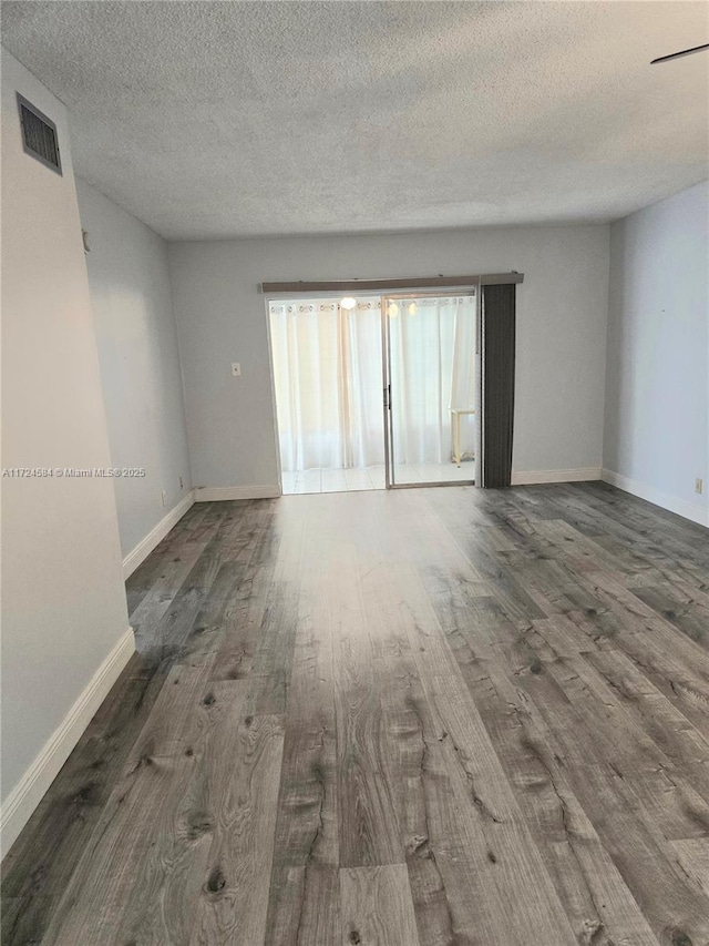 spare room featuring dark hardwood / wood-style flooring and a textured ceiling