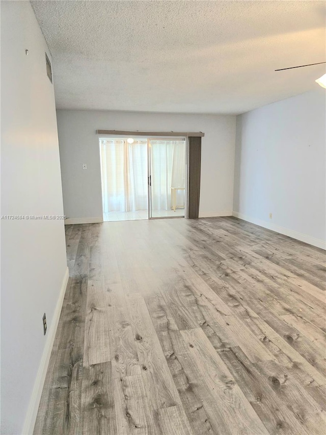 unfurnished room with a textured ceiling and light wood-type flooring