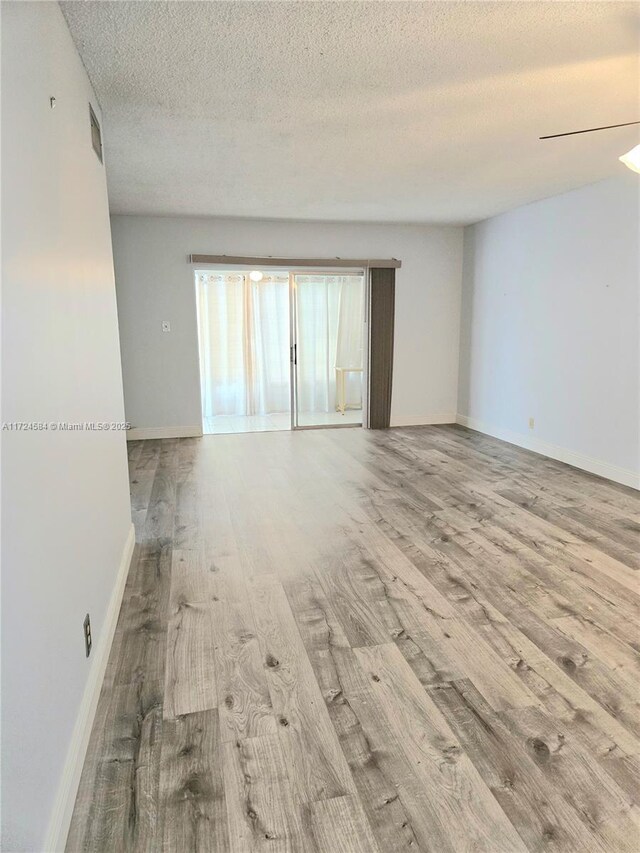 spare room with a textured ceiling and light wood-type flooring