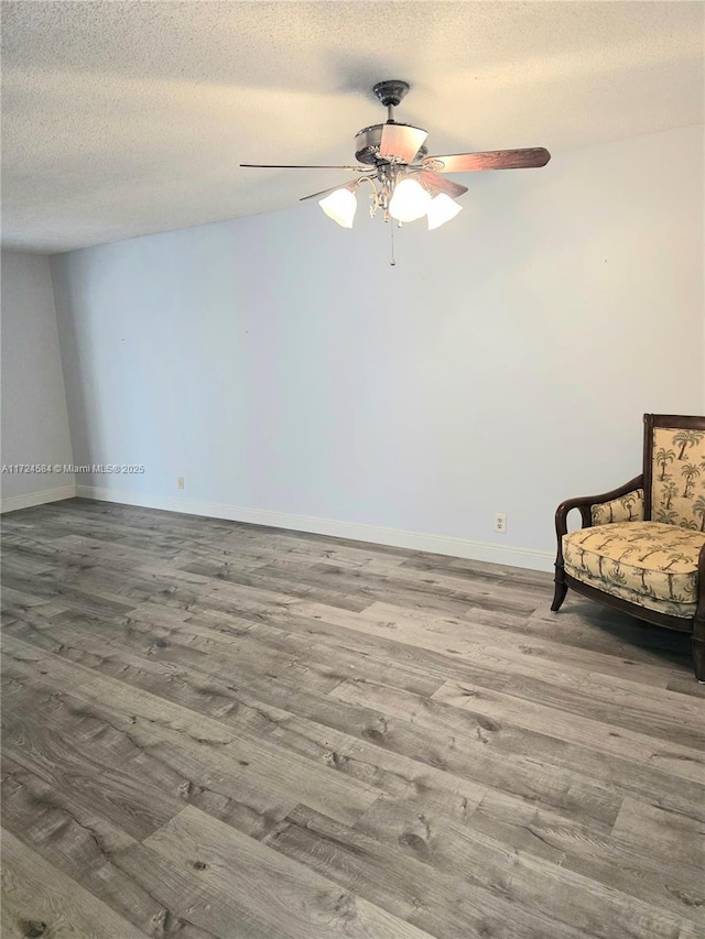 living area featuring hardwood / wood-style floors, ceiling fan, and a textured ceiling