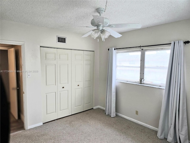 unfurnished bedroom featuring ceiling fan, a closet, carpet floors, and a textured ceiling